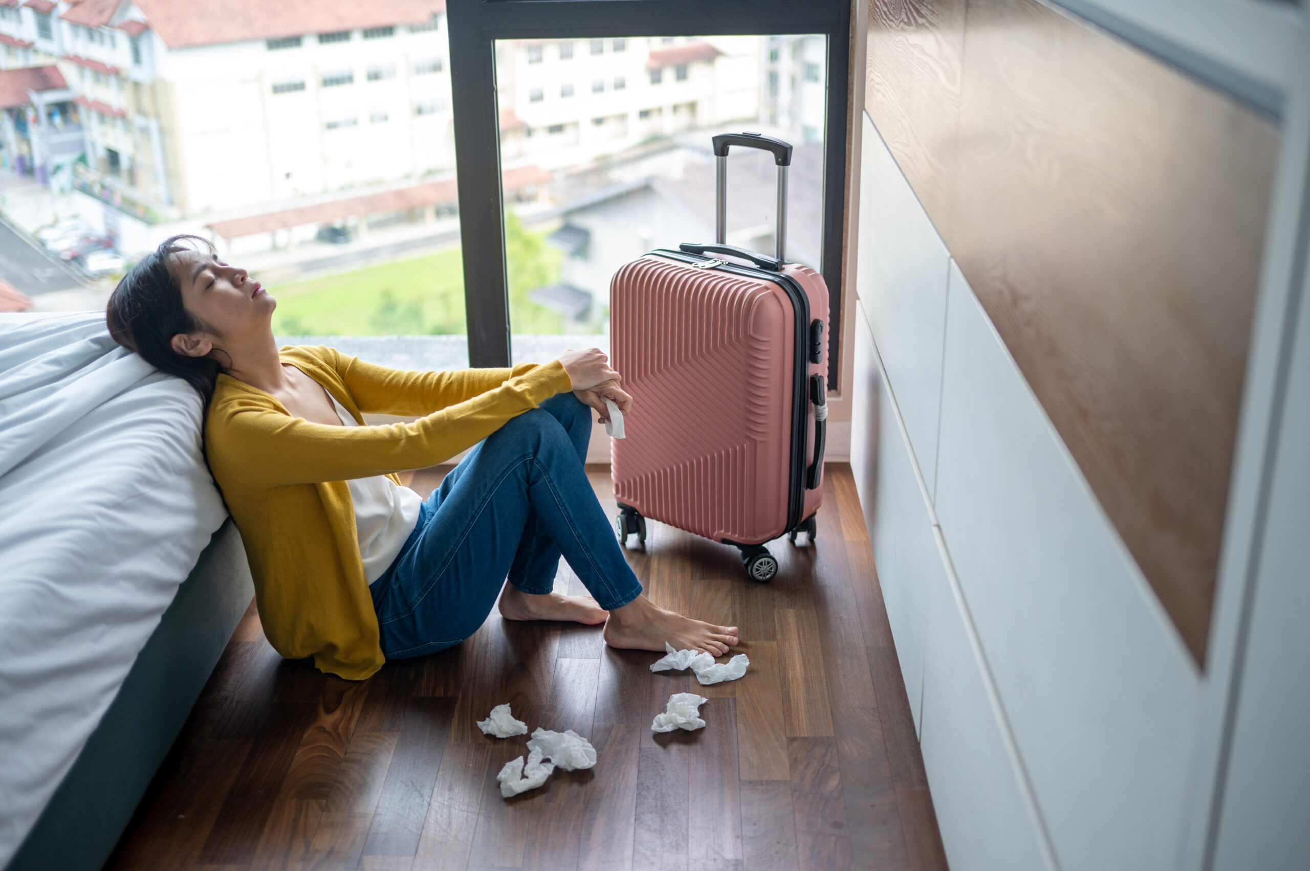Depressed Young Woman Sitting on Floor with Suitcase and Tissues iStock 2254354052 scaled